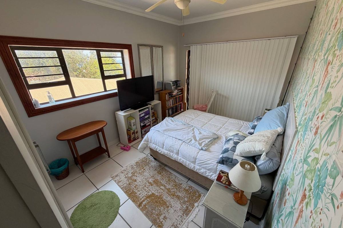 A bedroom featuring tiled flooring, a ceiling fan, and a large window with natural light.