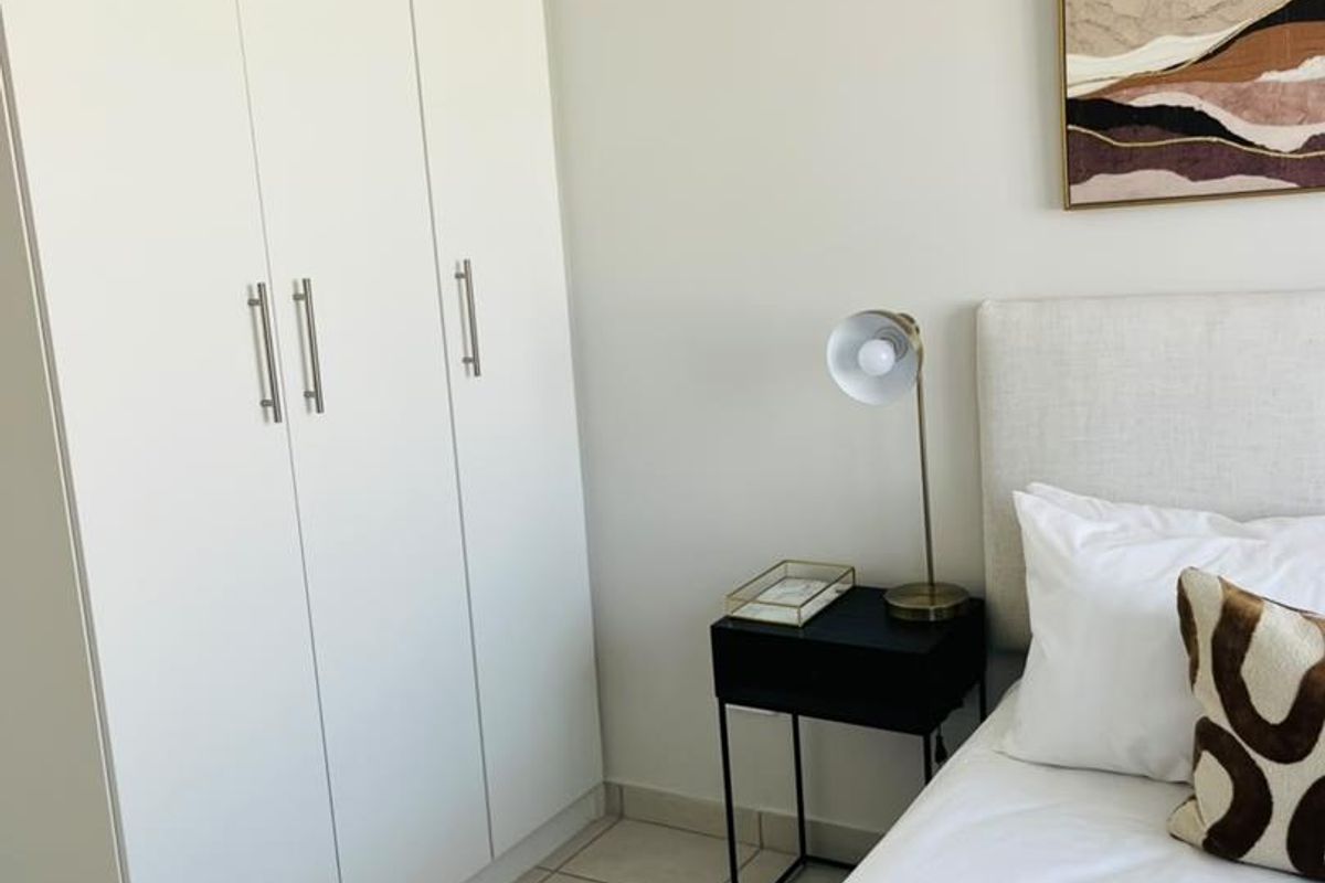 A well-maintained bedroom featuring neutral walls, tiled flooring, and a clean, modern built-in wardrobe.