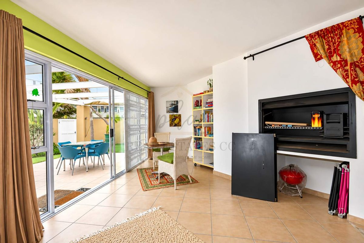 Spacious living area featuring a built-in braai and large sliding glass doors that open onto an outdoor patio space.