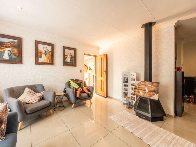 A living room featuring tiled flooring, a freestanding fireplace, and recessed lighting, providing a functional and comfortable space for relaxation.