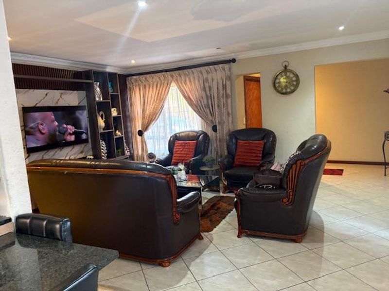A comfortable living room featuring tiled flooring, recessed ceiling lighting, and a built-in shelving unit with integrated television space.
