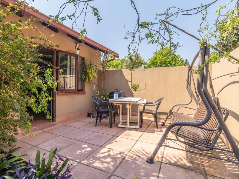 A private outdoor patio area featuring tiled flooring and a high boundary wall, providing a secluded space for outdoor relaxation.