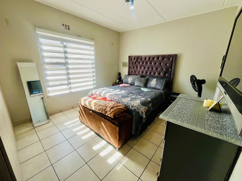 A bedroom featuring tiled flooring and roller blinds, providing a functional space with neutral wall finishes.