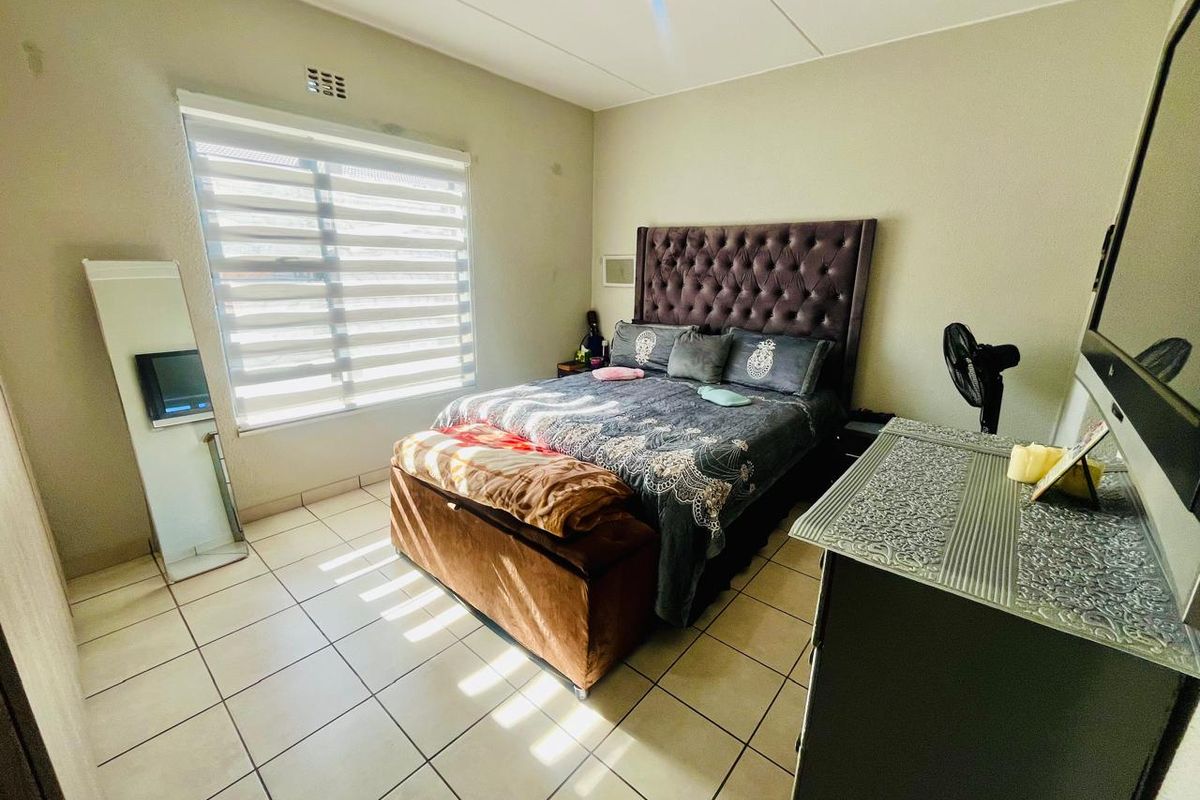 A bedroom featuring tiled flooring and roller blinds, providing a functional space with neutral wall finishes.