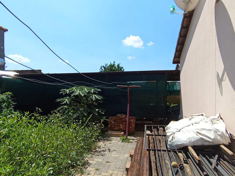 Rear exterior area featuring paved ground, solar geyser installation, and perimeter security fencing.