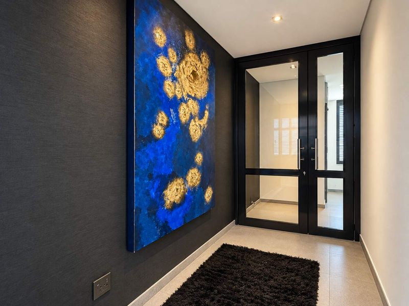 Modern entrance foyer featuring a sleek double glass door, textured dark feature wall, and recessed downlighting, creating a sophisticated and welcoming transition space.