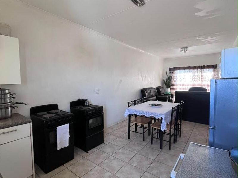 Open-plan living and kitchen area featuring tiled flooring, basic cabinetry, and a functional layout suitable for modern updates.