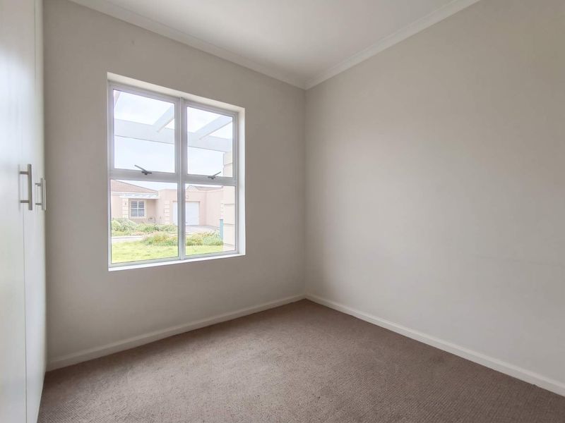 A clean, empty bedroom featuring neutral walls, carpeted flooring, and built-in cupboards, offering a blank canvas for personalization.