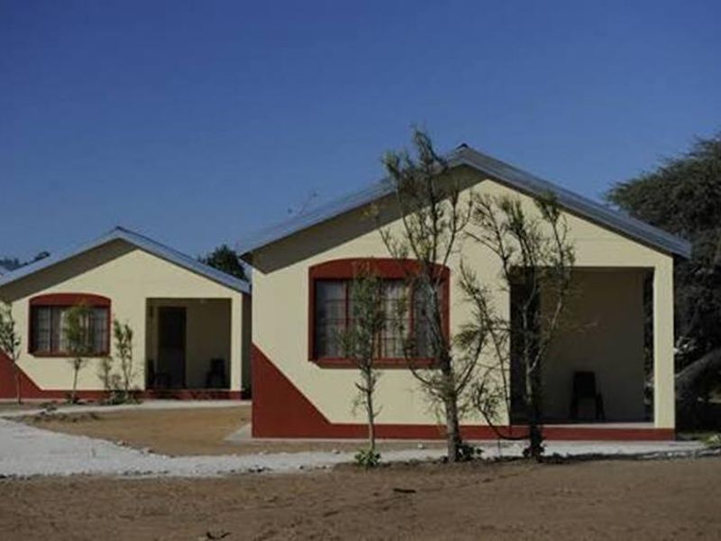 A view of two matching farm-style residential units featuring covered patios, metal roofing, and painted exterior masonry finishes.