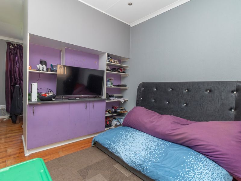 A bedroom featuring built-in purple cabinetry with integrated shelving and laminate flooring, offering functional storage space.
