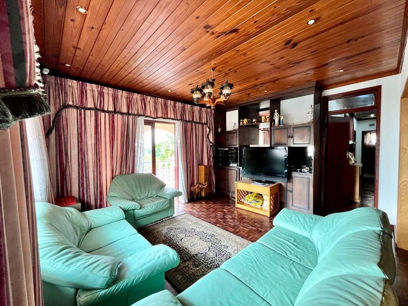 A living room featuring a warm timber tongue and groove ceiling, parquet flooring, and extensive built-in wooden cabinetry with integrated shelving.