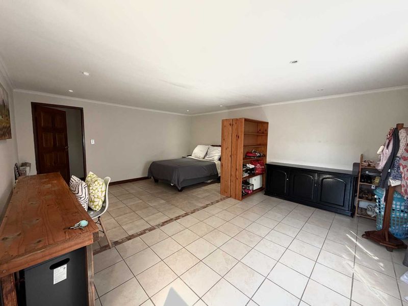 Spacious bedroom featuring neutral tiled flooring and recessed downlighting, offering a versatile layout for various furniture arrangements.