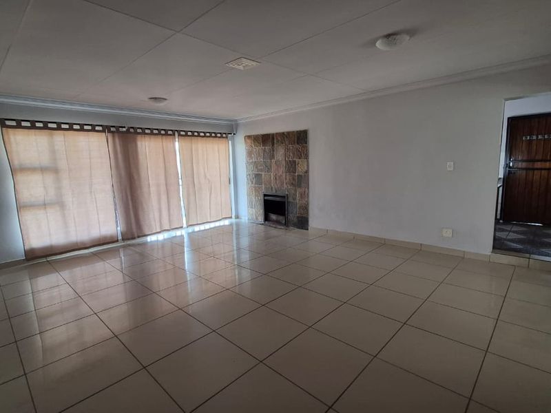Spacious living area featuring large sliding glass doors, tiled flooring, and a built-in fireplace, offering a blank canvas for interior design.