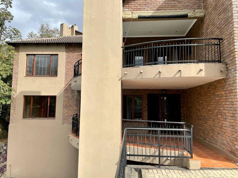 Rear view of the apartment building featuring multi-level balconies with metal railings, brick facade, and tiled outdoor flooring.