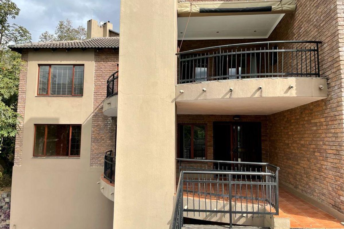 Rear view of the apartment building featuring multi-level balconies with metal railings, brick facade, and tiled outdoor flooring.