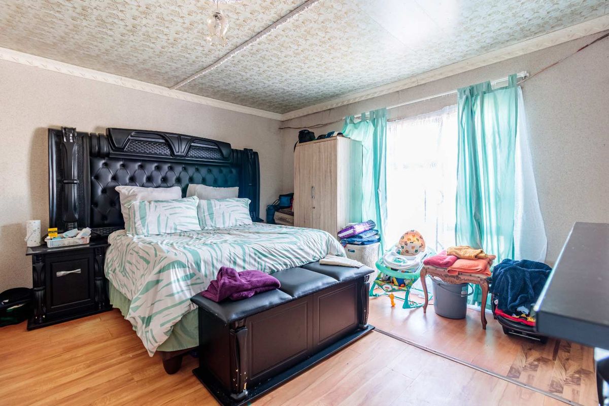 A bedroom featuring laminate flooring and a textured ceiling, offering a functional space with natural light from the window.