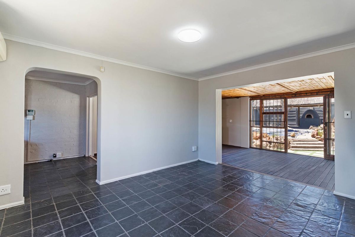 Spacious living area featuring dark slate tile flooring, an arched entryway, and direct access to an outdoor wooden deck through sliding glass doors.