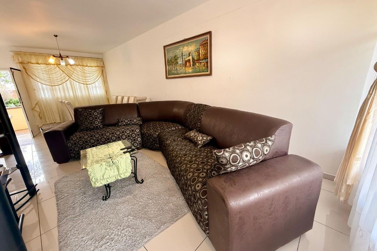 A spacious living area featuring neutral tiled flooring and access to an adjoining balcony, providing a functional and comfortable layout.