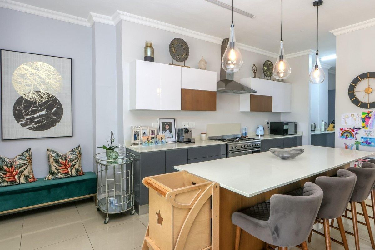 Modern kitchen featuring a central island with quartz countertops, two-tone cabinetry, gas stove, extractor fan, and stylish pendant lighting.