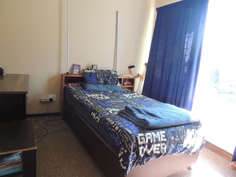 A functional bedroom featuring carpeted flooring and a sliding glass door providing natural light.