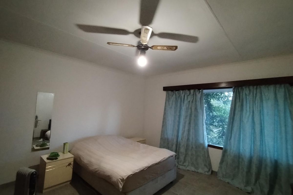 A bedroom featuring tiled flooring and a ceiling fan, requiring cosmetic updates to modernize the space.