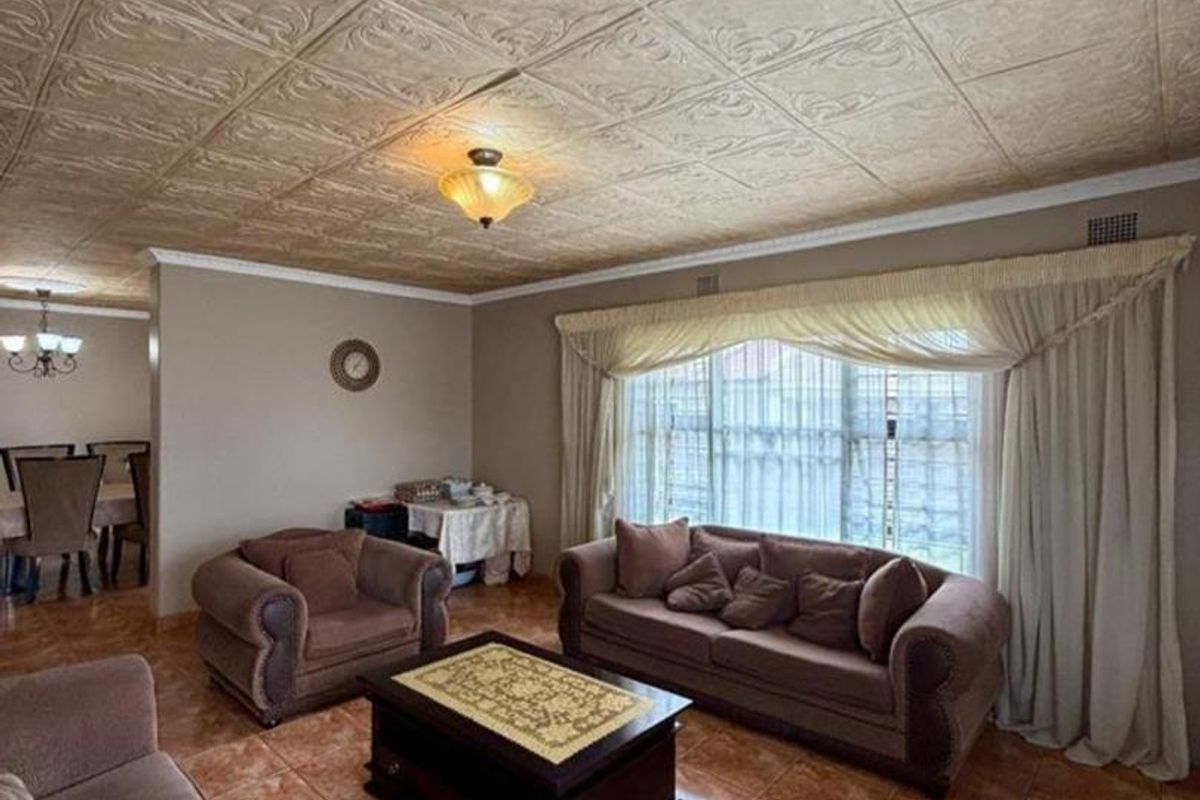 Spacious living room featuring decorative ceiling tiles, ceramic floor tiling, and large windows with integrated curtain rails.