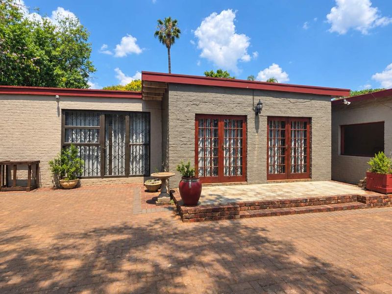 Rear exterior view of the property featuring a brick-paved patio area, double french doors, and secure access points with a low-maintenance brick facade.