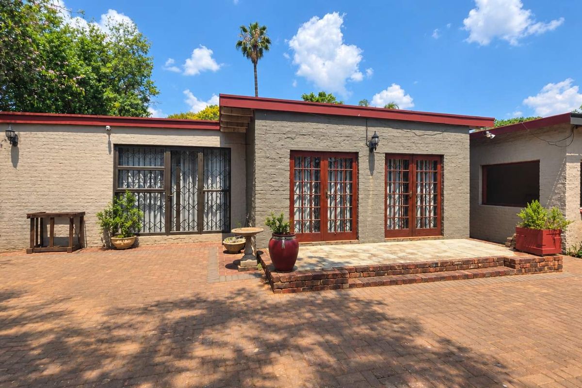 Rear exterior view of the property featuring a brick-paved patio area, double french doors, and secure access points with a low-maintenance brick facade.