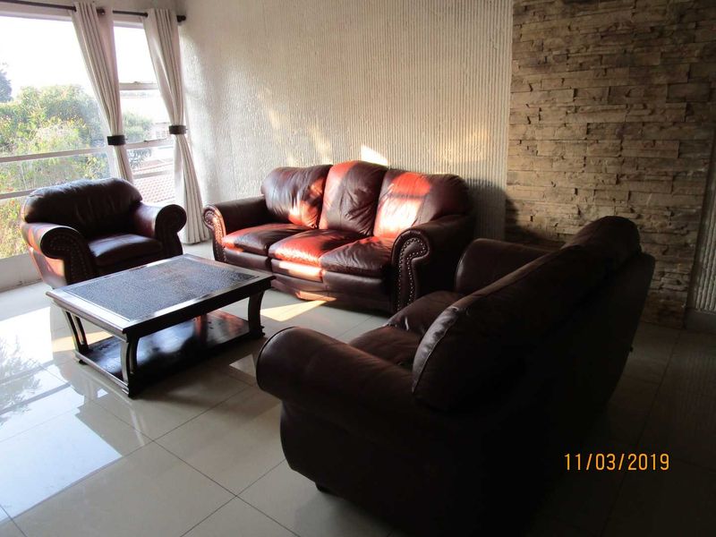 A living room featuring large format floor tiles, a textured feature wall, and a stone-clad accent wall with access to a balcony.