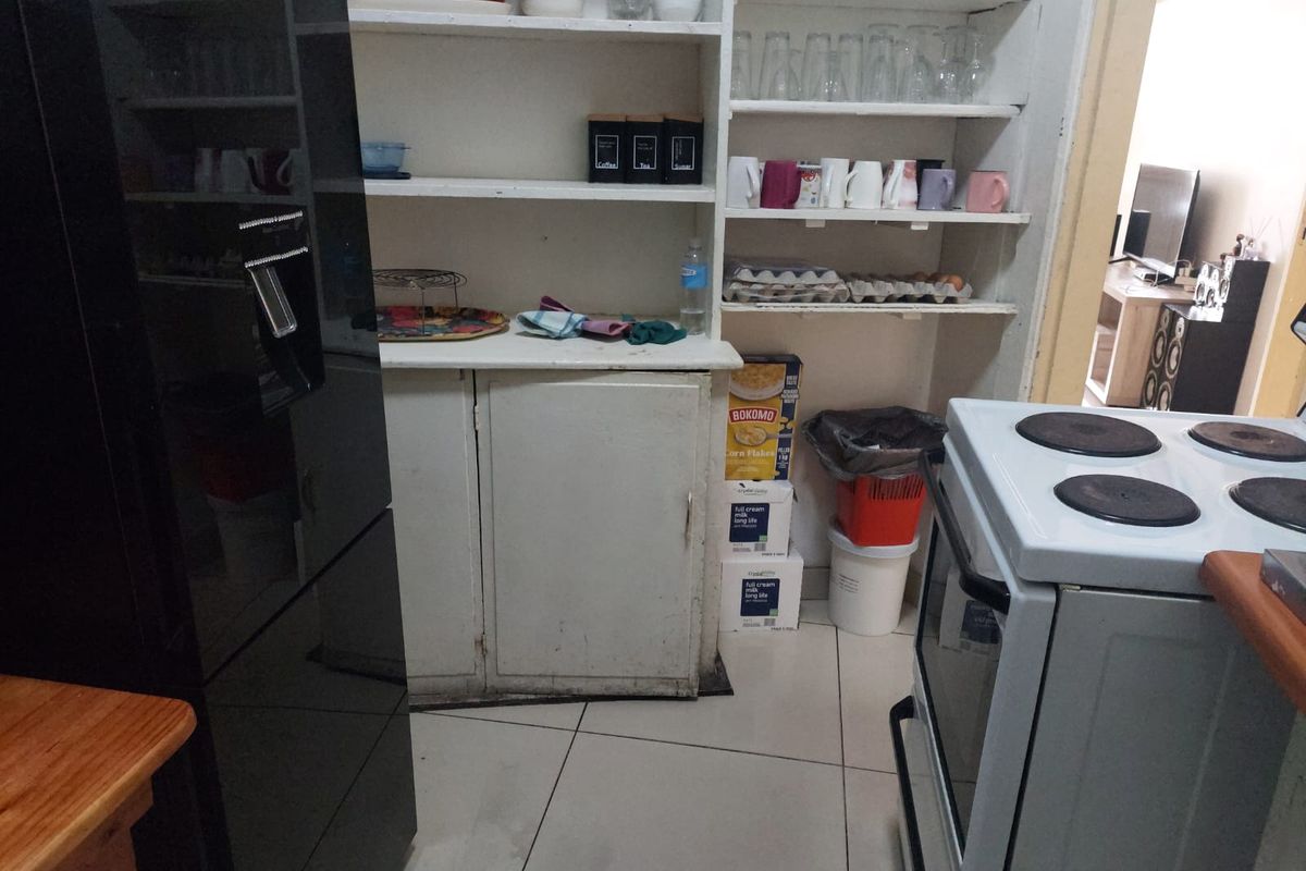 A functional kitchen area featuring built-in cabinetry, open shelving for storage, and tiled flooring, requiring cosmetic updates to improve its overall aesthetic.