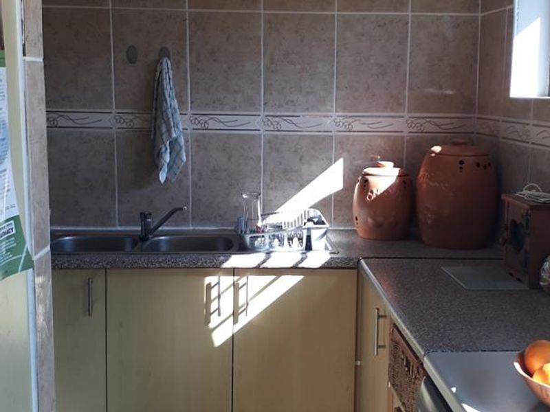 A functional laundry area featuring a double sink, laminate cabinetry, tiled splashback, and durable floor tiles.