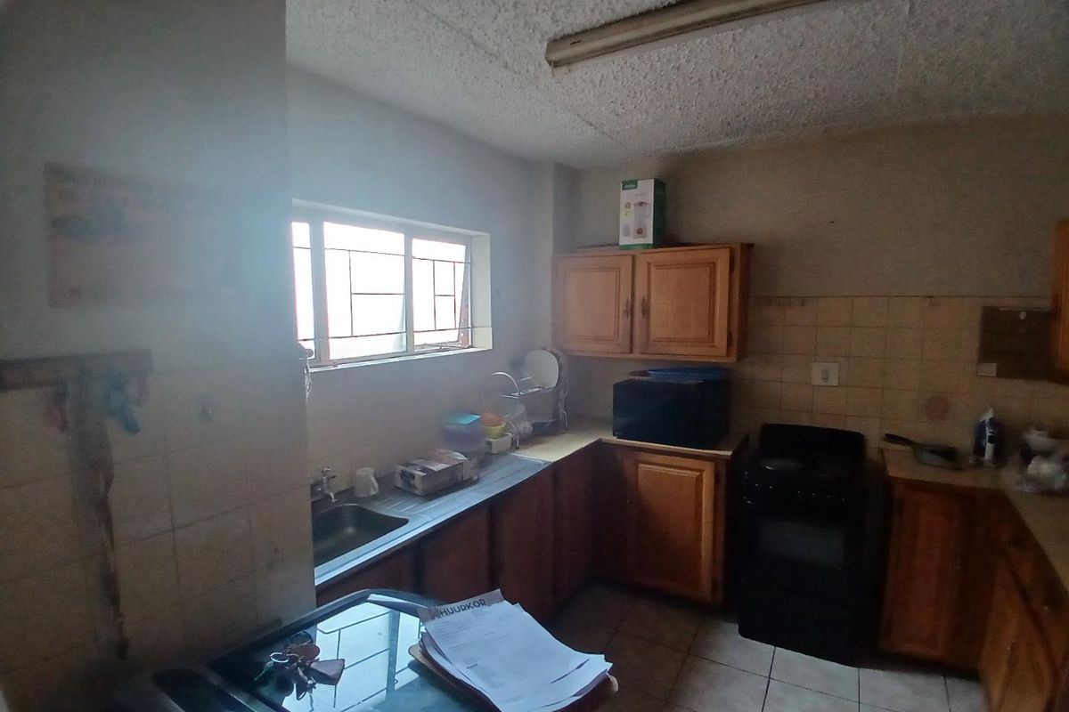 A dated kitchen featuring wooden cabinetry, tiled splashbacks, and a functional layout with a built-in stove and sink area.