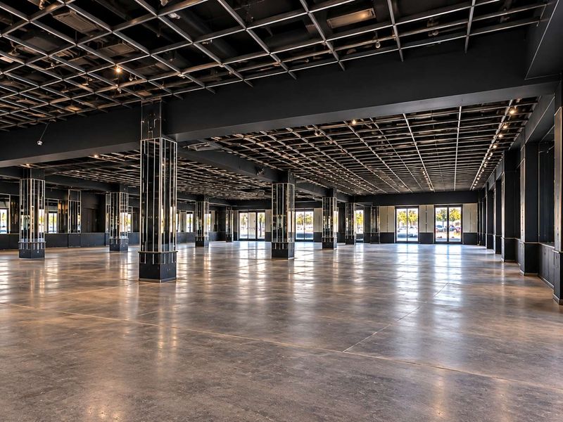 Expansive open-plan commercial space featuring polished concrete floors, mirrored support columns, and a modern exposed grid ceiling with integrated lighting.