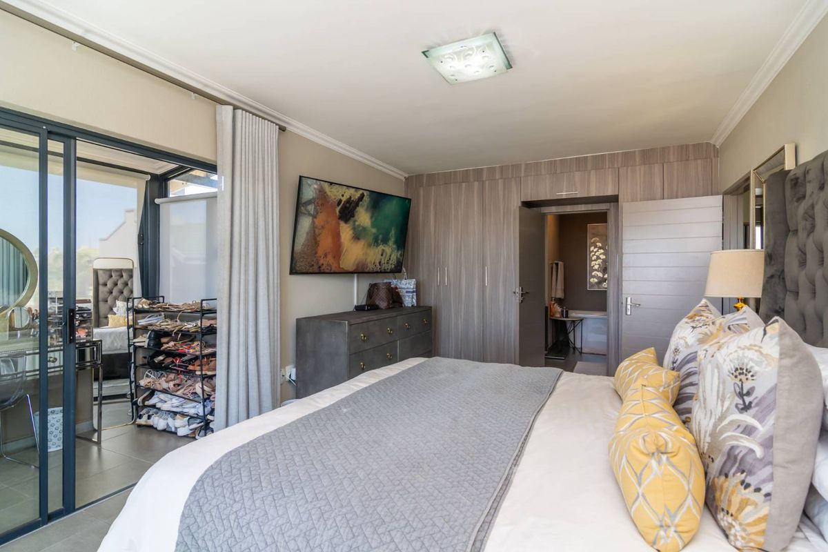 A well-maintained bedroom featuring built-in wooden cabinetry, crown molding, and sliding glass doors leading to an adjacent patio area.