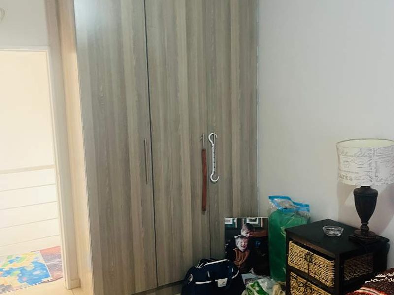 A bedroom featuring a modern wood-grain built-in wardrobe and tiled flooring.