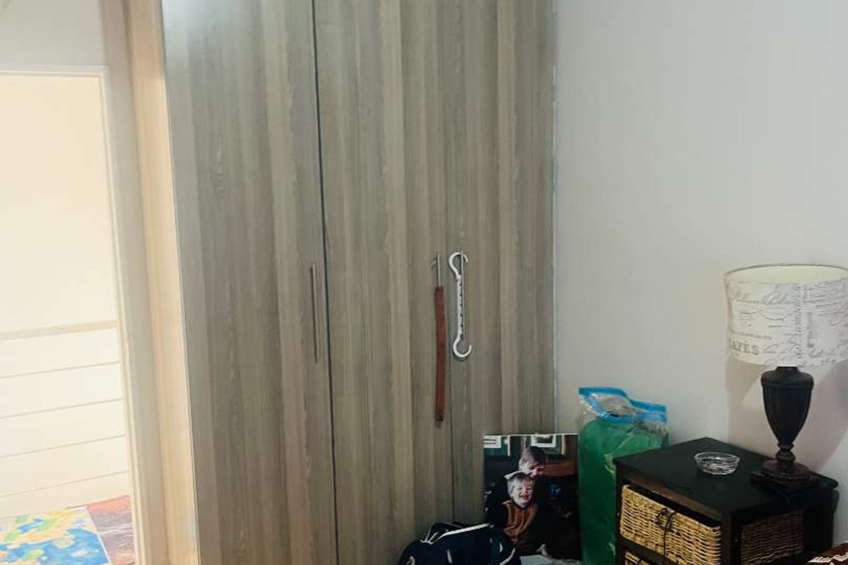 A bedroom featuring a modern wood-grain built-in wardrobe and tiled flooring.