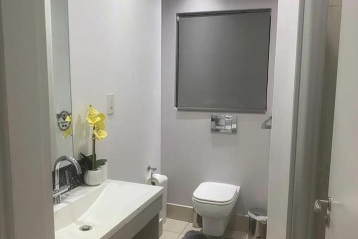 Modern bathroom featuring a wall-mounted toilet, vanity basin with chrome fixtures, recessed lighting, and neutral tiled flooring.