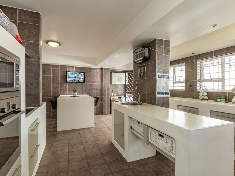 Spacious kitchen featuring a central island, built-in oven and microwave, tiled finishes, and ample counter space with integrated sink.