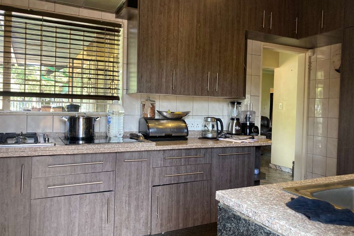 Functional kitchen featuring wood-grain cabinetry, stone-look countertops, integrated gas hob, and extractor fan with tiled splashbacks.