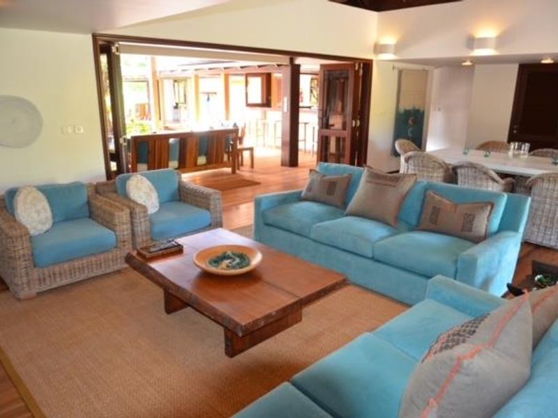 Spacious open-plan living and dining area featuring timber flooring, recessed lighting, and large folding doors opening to an outdoor patio space.
