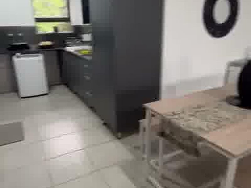 Open plan kitchen and dining area featuring modern dark cabinetry, tiled flooring, and functional workspace.