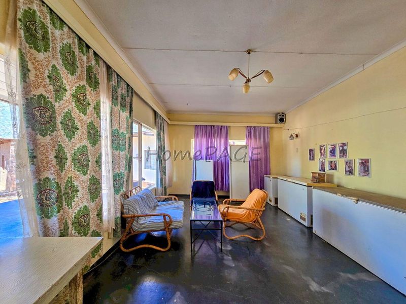 A spacious living area featuring large windows, neutral wall finishes, and a central ceiling light fixture, offering a blank canvas for renovation.