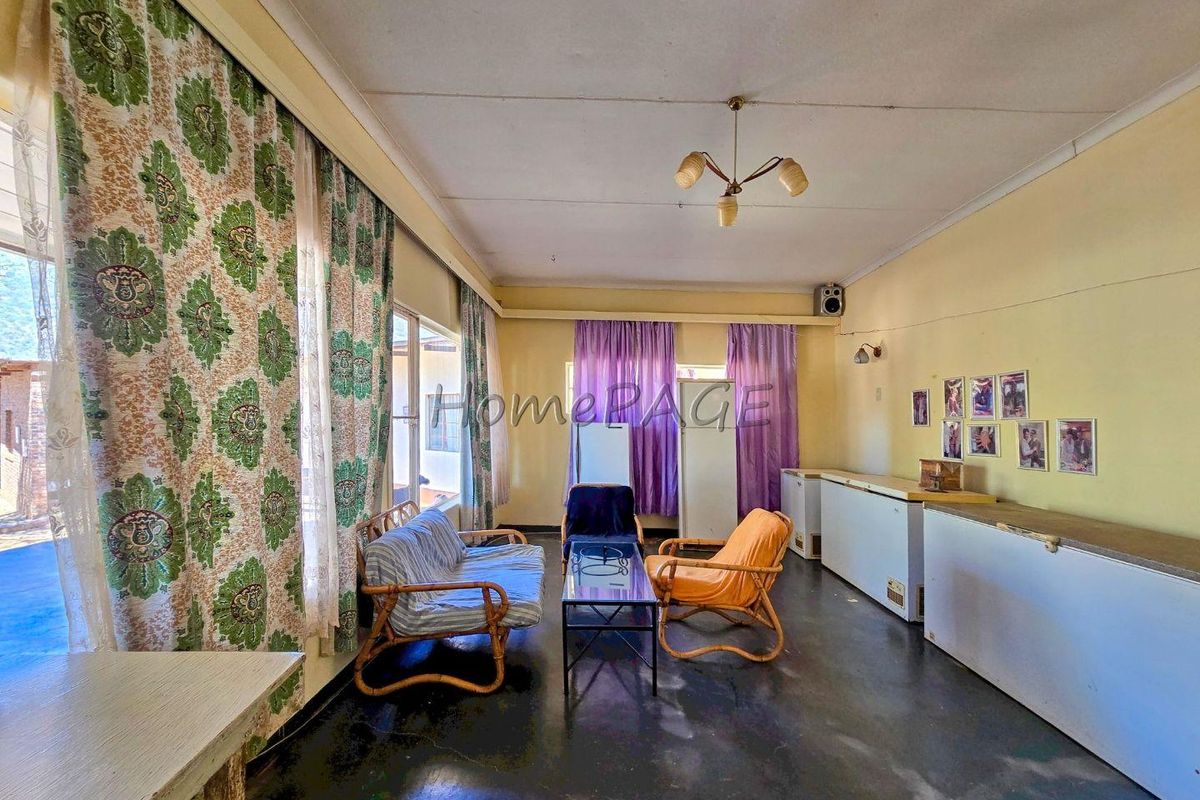 A spacious living area featuring large windows, neutral wall finishes, and a central ceiling light fixture, offering a blank canvas for renovation.