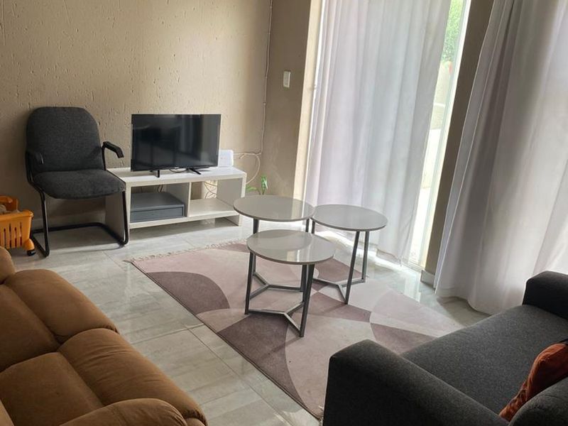 A living room featuring tiled flooring and a sliding glass door providing access to the exterior.