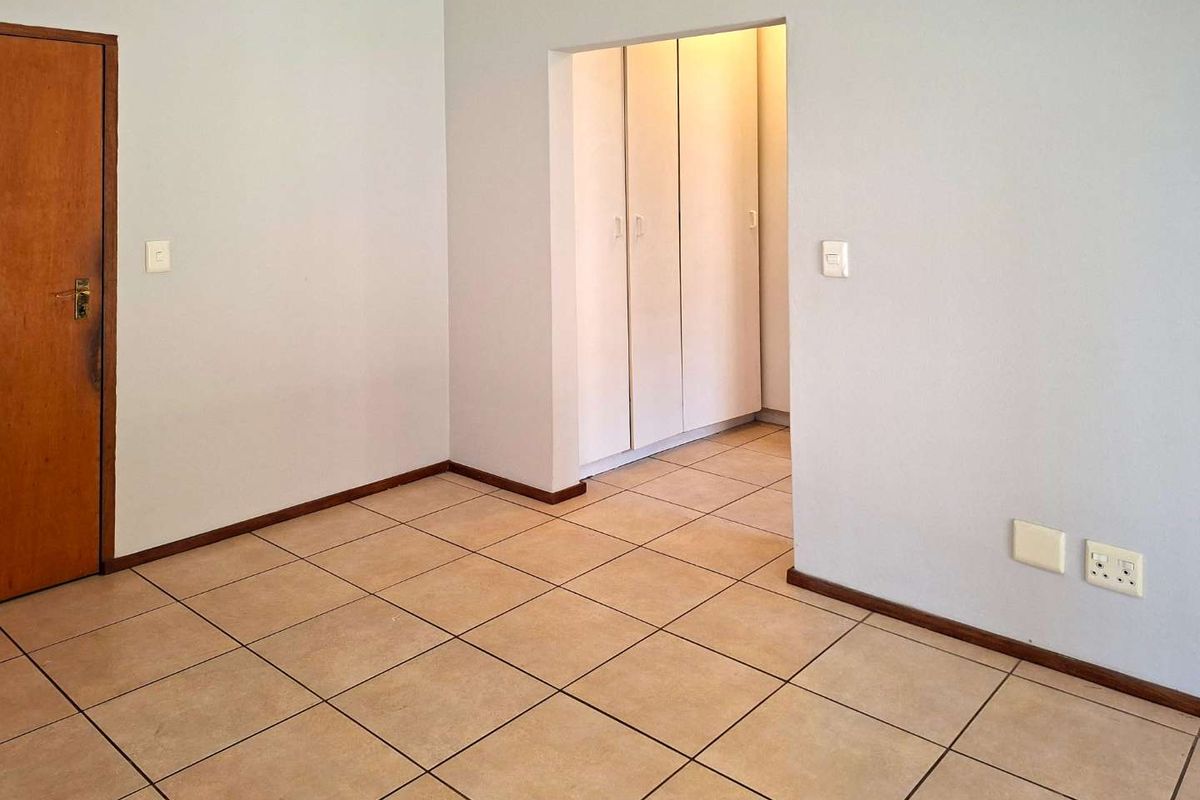 An empty bedroom featuring neutral tiled flooring, built-in cupboards, and a clean, minimalist layout ready for personalization.