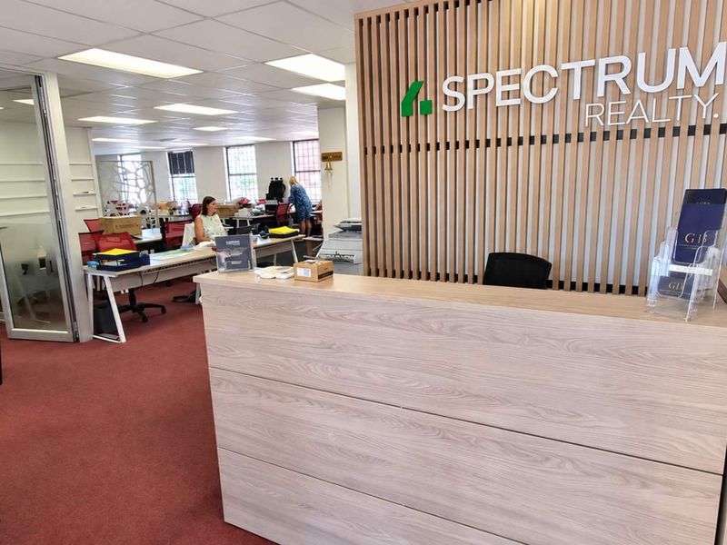 Professional office reception area featuring a modern timber slat feature wall, glass partitions, and a clean, functional layout.