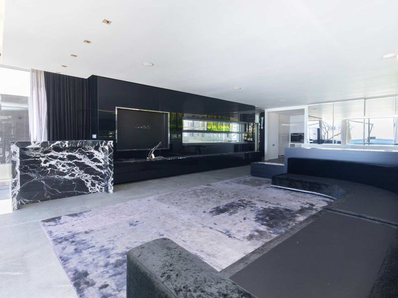 Modern open-plan living area featuring high-end marble accents, sleek built-in cabinetry, recessed lighting, and large format floor tiles.