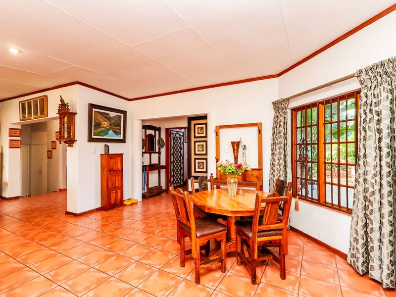A dining area featuring terracotta floor tiles, timber-framed windows with security bars, and a coved ceiling, offering a traditional and functional living space.
