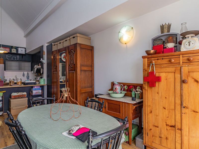 Open plan living and dining area featuring a compact kitchen with tiled backsplash and vaulted ceilings, creating a bright and functional living space.