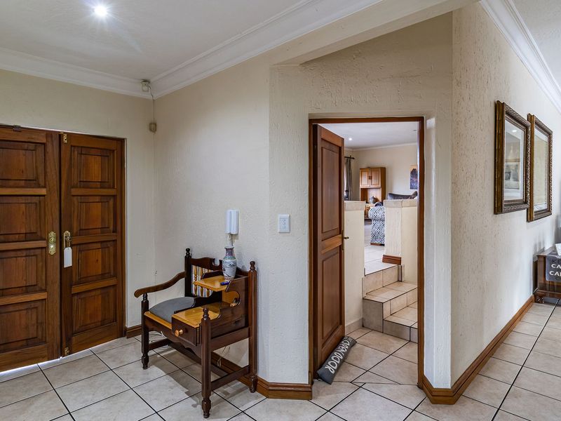 A spacious tiled hallway featuring classic wooden double doors, coved cornicing, and an intercom system, providing access to adjacent living areas.